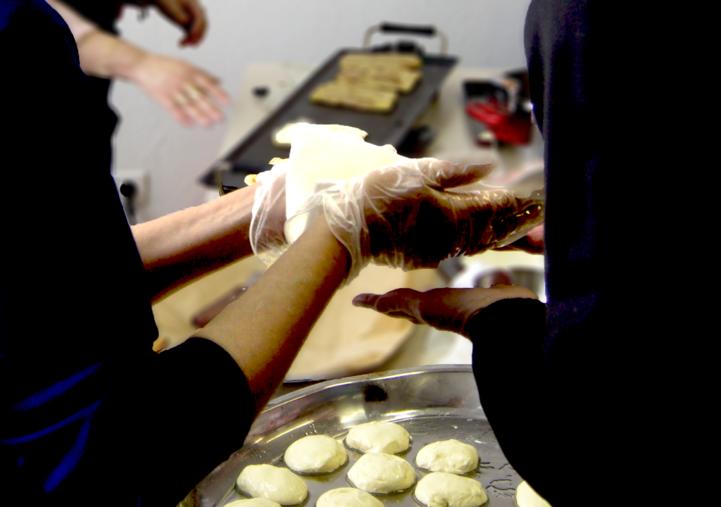 les mains d'une cuisinière donnant à une convive le Mahjouba qu'elle vient de cuire lors d'une animation traiteur.